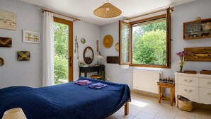 A bedroom with a bed, a dresser, a window with a view, and various wall decorations.
