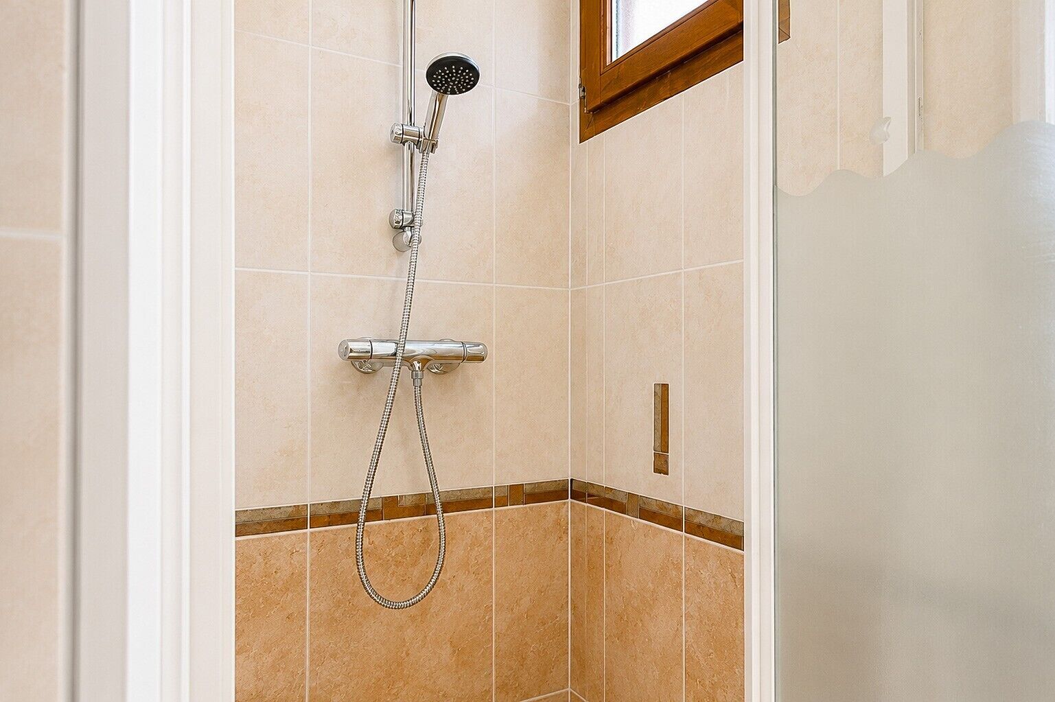 A shower with a handheld showerhead and a wall-mounted control valve.