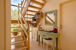 Una escalera conduce a una zona de altillo con barandilla de madera, un escritorio con espejo y un hervidor rojo.