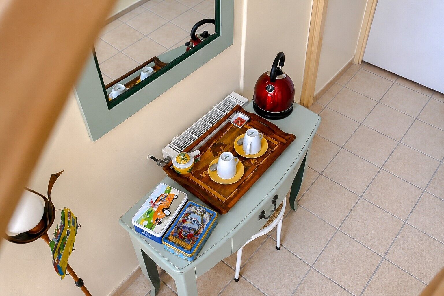 A kitchen area with a kettle, a tray with cups, a microwave, and a small table with a book.