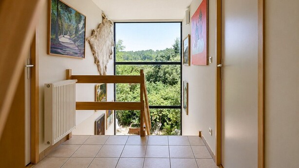 A hallway with a view of a forest, a radiator, and artwork on the walls.