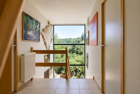 Un pasillo con vistas a un bosque, un radiador y obras de arte en las paredes.