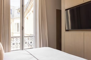 Ein Hotelzimmer mit Bett, Wand-Fernseher und Blick auf den Balkon.