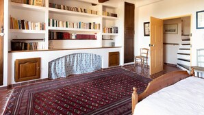 Un dormitorio con una cama grande, cabecera de madera, estantería empotrada, alfombra estampada y una escalera.