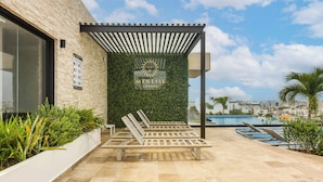 Un área de estar exterior moderna con pérgola, piscina y vistas a la ciudad.