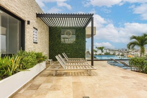 A modern outdoor seating area with a pergola, a pool, and a view of the cityscape. - Walk to Beach & 5th Ave! Chic Studio w/ Patio (Playa del Carmen)