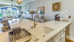 A kitchen with a large island, a sink, and a chandelier.