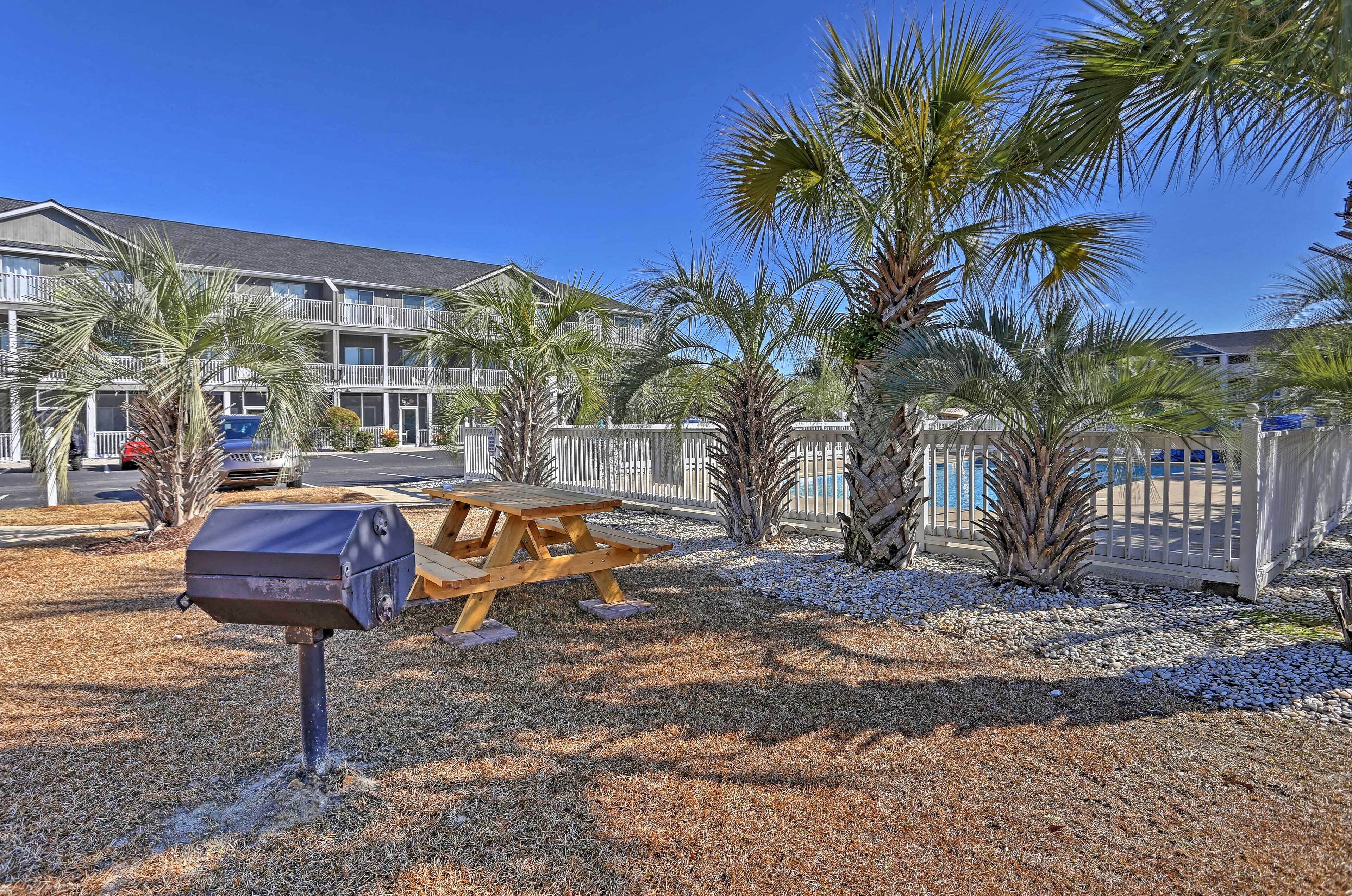 A building with a pool, palm trees, and a picnic table.