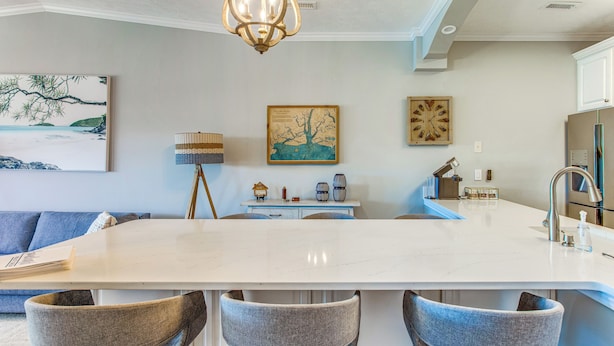 A modern kitchen with a large island, bar stools, and a dining area.
