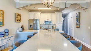 A kitchen with white cabinets, a large island, and blue chairs.