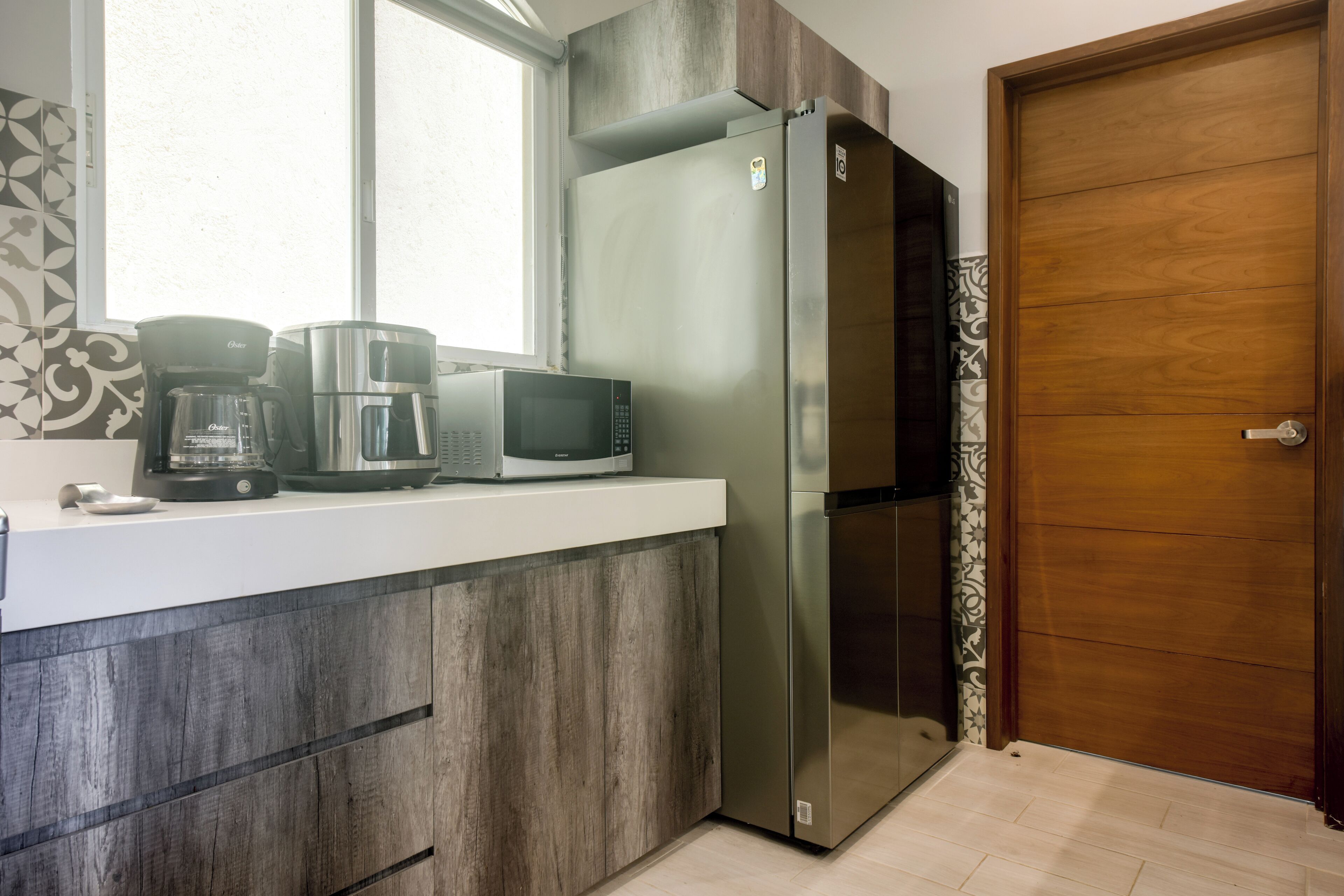 A kitchen with a stainless steel refrigerator, a microwave, and a coffee maker on the counter.