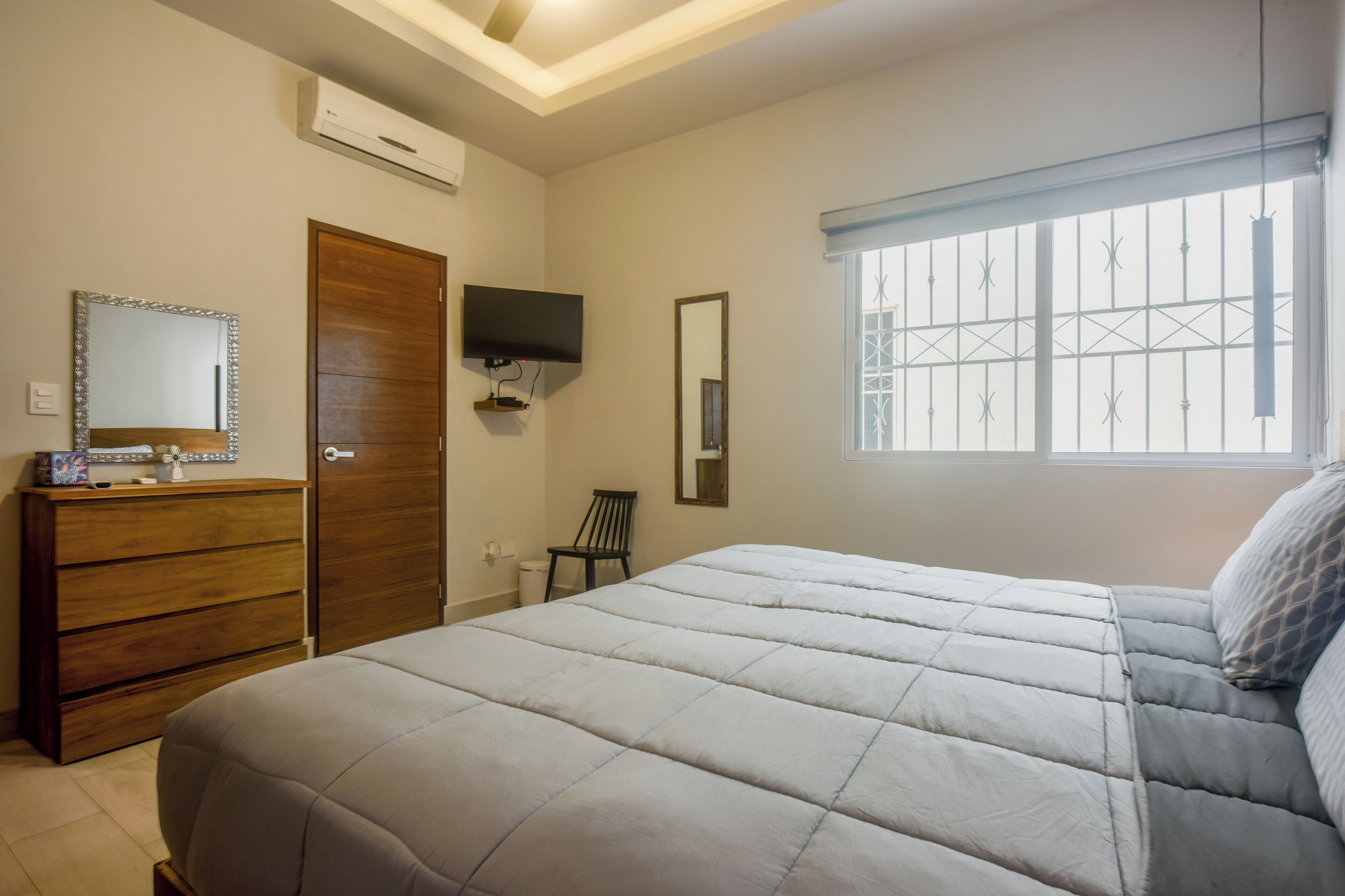 Ein Schlafzimmer mit Bett, Schminktisch, Fernseher, Sessel und Fenster mit Blick.