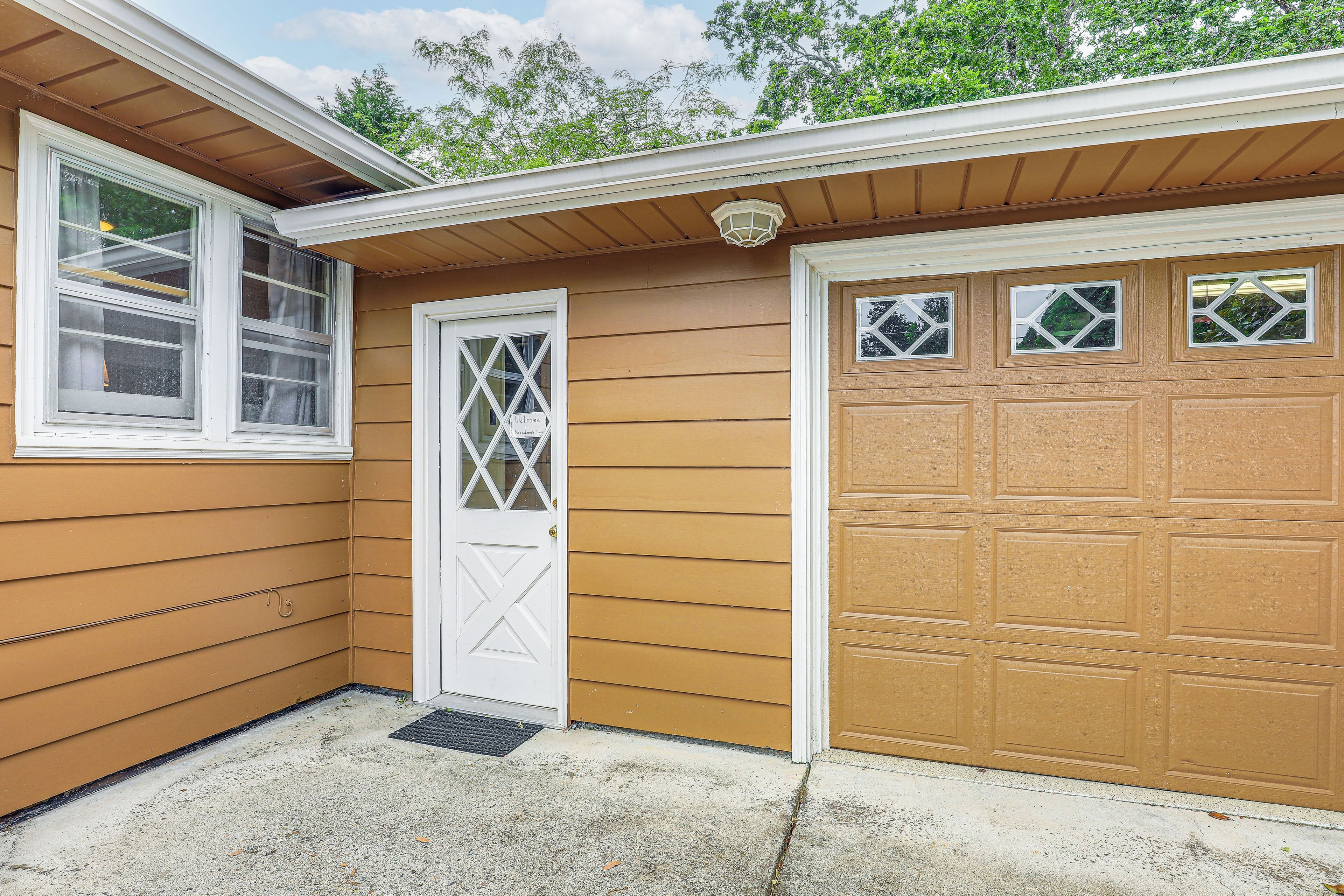 Un garage avec une porte blanche et une porte de garage dotée de fenêtres en forme de losange.
