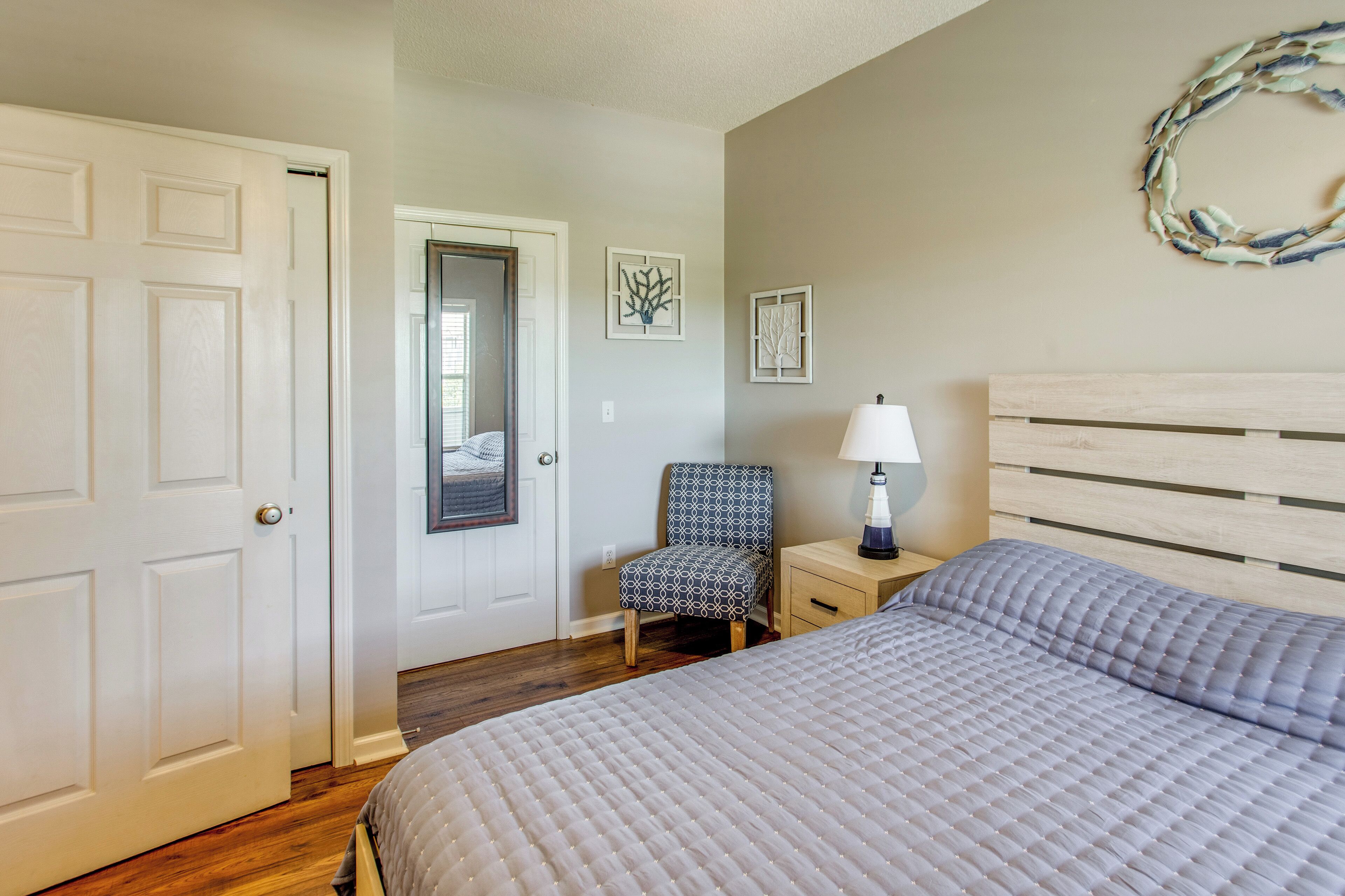 A bedroom with a bed, a chair, a nightstand, and a door.