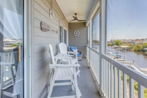 A balcony with white Adirondack chairs, a small table, and a view of a water body with docks. - Waterfront Condo w/ Views & Pool in Little River (Little River)