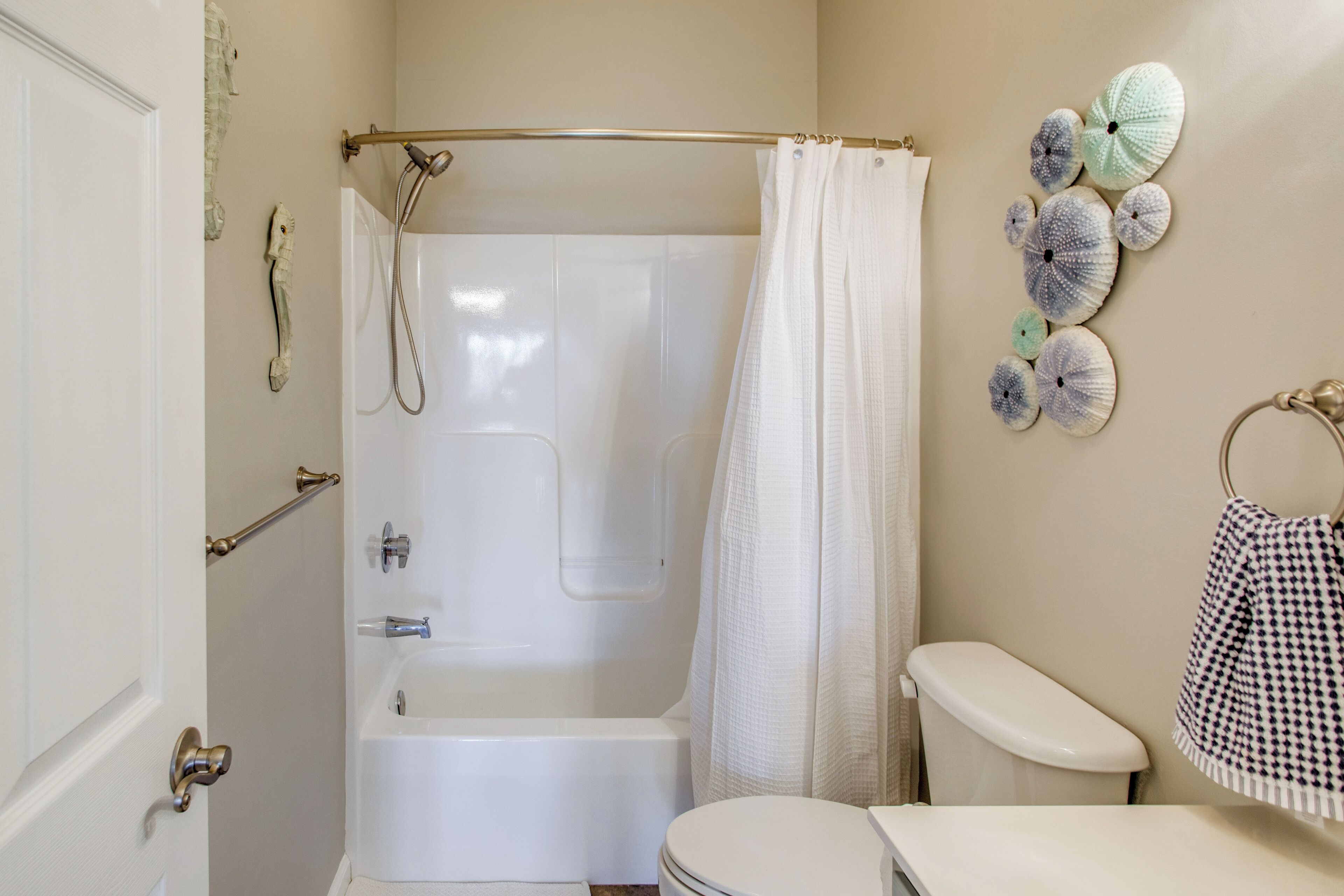 A bathroom with a bathtub, toilet, and a towel rack.