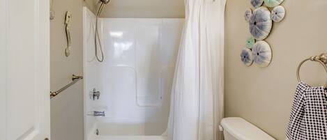 A bathroom with a bathtub, toilet, and a towel rack.