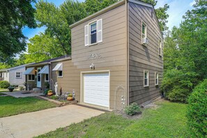 Une maison à deux étages avec un garage, un porche à l’avant et un petit jardin.