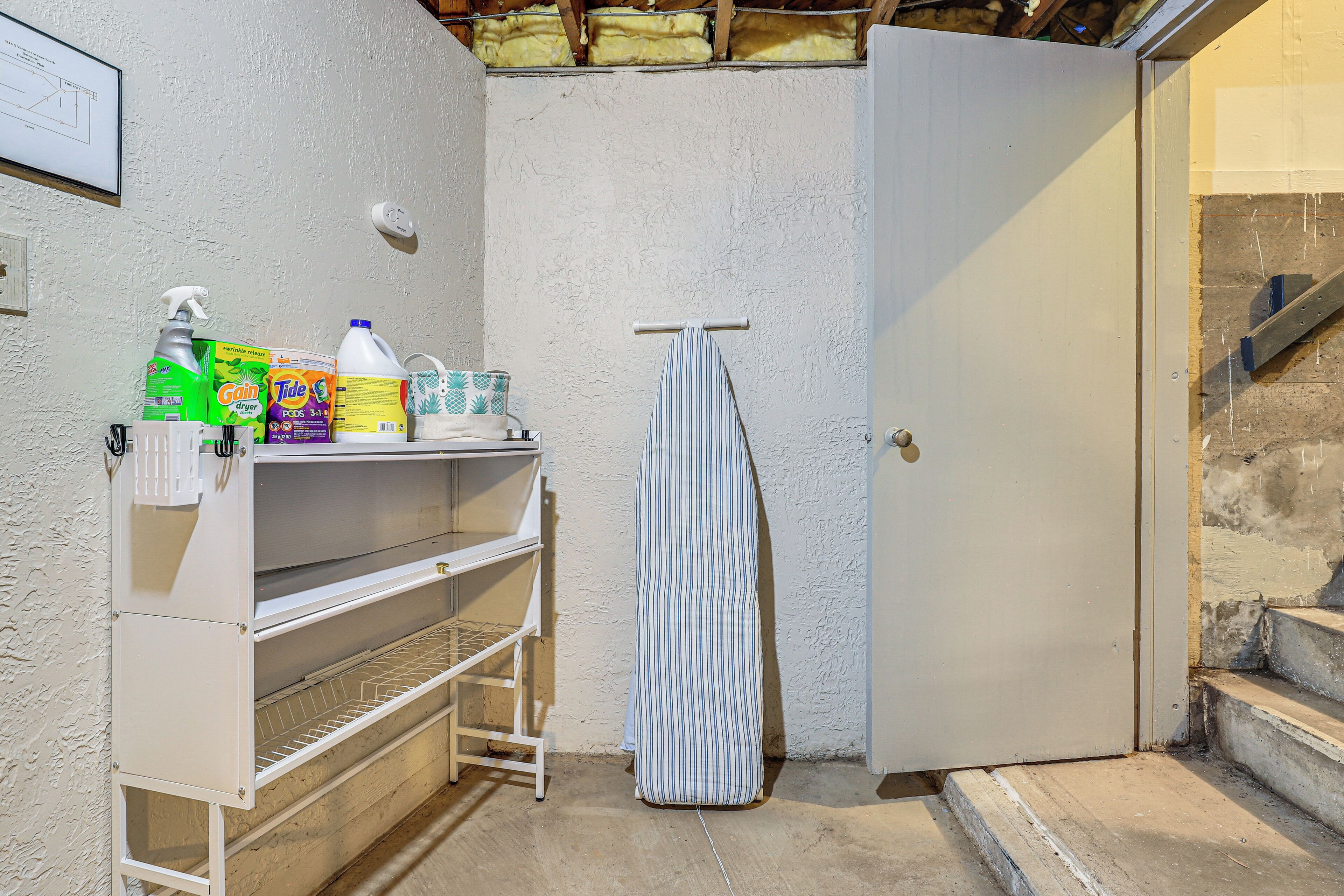 A utility room with a white shelf holding cleaning supplies, a striped towel hanging on a rack, and a closed door.