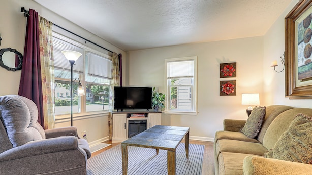 Una sala de estar con sofá, sillón, televisor y una mesa.