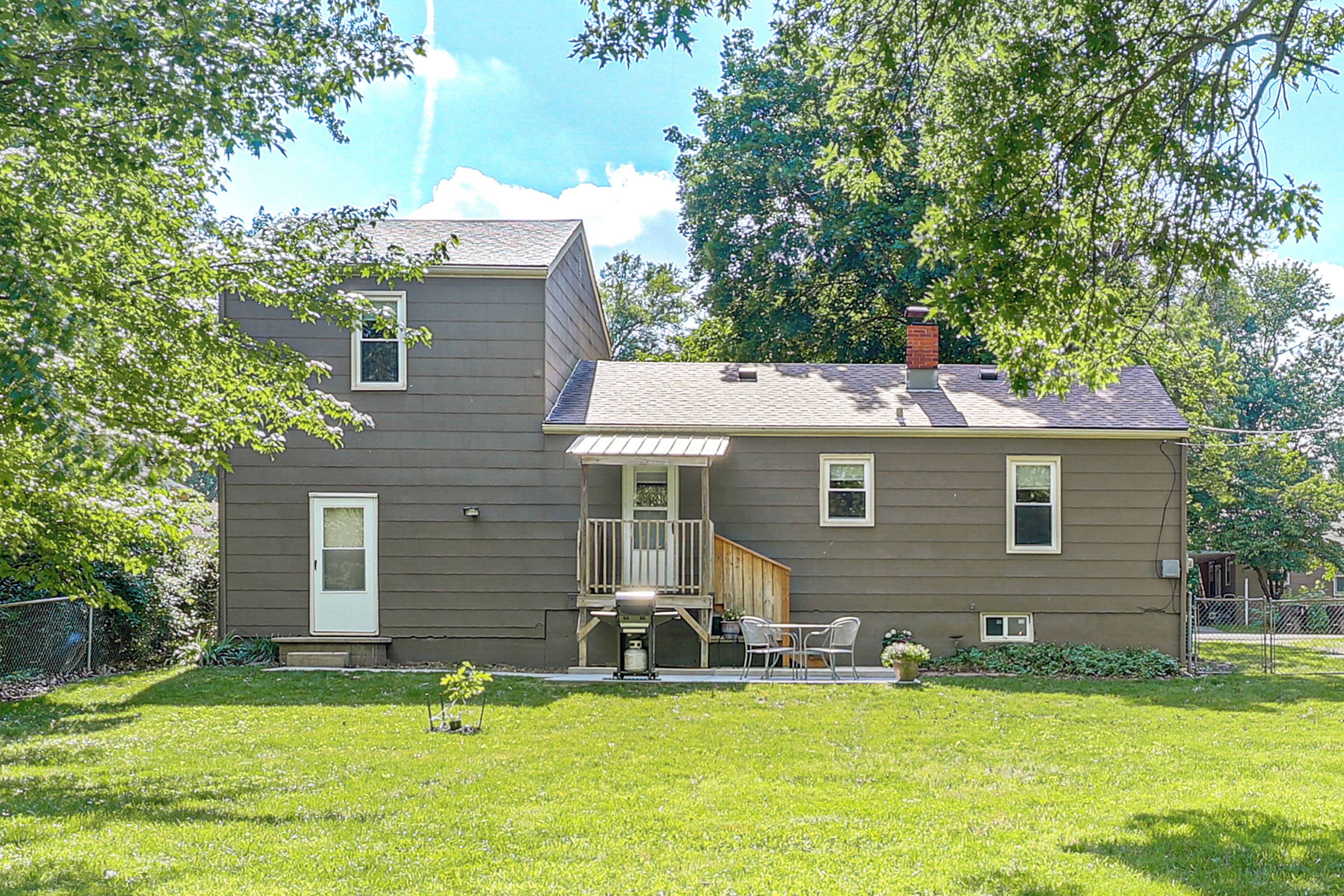 A two-story house with a front porch, a small deck, and a chimney.