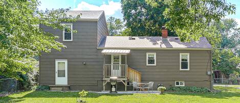 A two-story house with a front porch, a small deck, and a chimney.