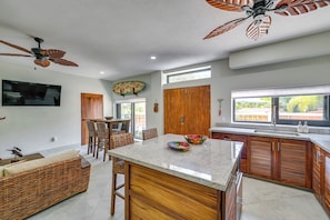 A modern kitchen with a central island, wooden cabinets, and a ceiling fan.