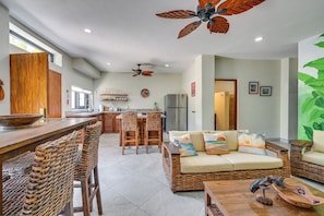 A spacious kitchen with a dining area, wicker furniture, and a ceiling fan.