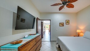 A bedroom with a bed, a wooden dresser, a TV mounted on the wall, and a ceiling fan. - Walk to Beach & Dining! Chic San Pancho Casita (San Francisco)