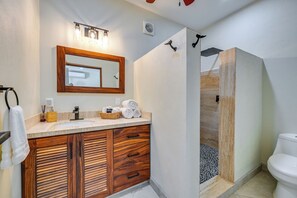 Une salle de bain avec un meuble-lavabo en bois, un miroir, un lavabo et un espace douche.