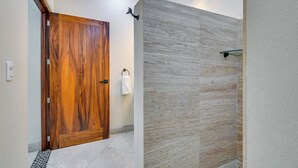 A bathroom with a wooden door, a glass shower enclosure, and a tiled floor. - Walk to Beach & Dining! Chic San Pancho Casita (San Francisco)