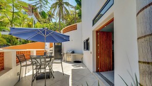 A patio with a table and chairs, a blue umbrella, and a grill. - Walk to Beach & Dining! Chic San Pancho Casita (San Francisco)