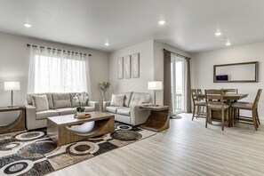 A modern living room with a sofa, coffee table, and dining table.