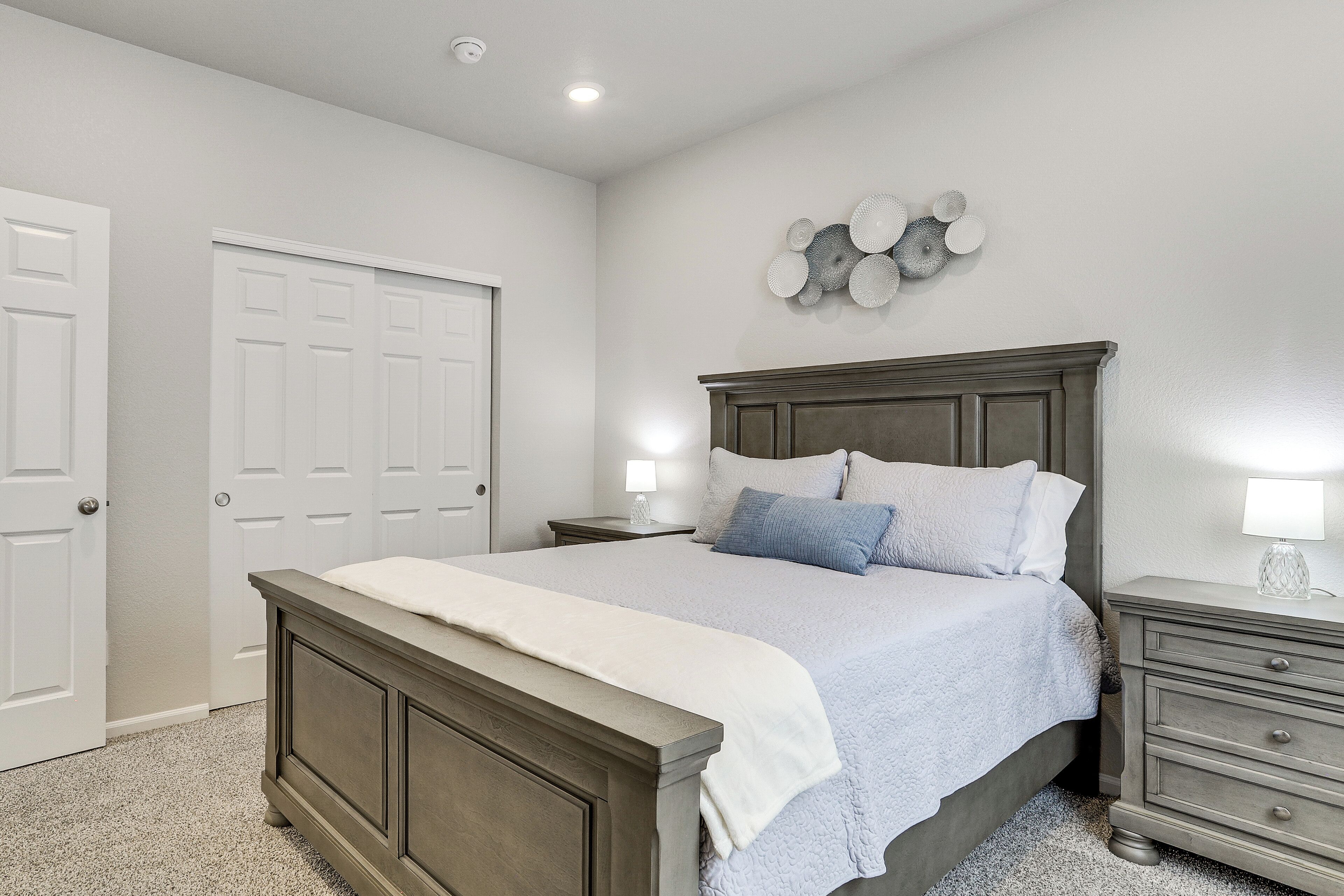 A bedroom with a bed, nightstands, a dresser, and a door.