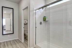Ein Badezimmer mit Glasdusche, einer weißen Toilette und einem Spiegel an der Wand.