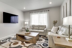 A modern living room with a sofa, coffee table, and a flat-screen TV mounted on the wall.