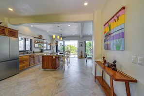 A spacious kitchen with a central island, wooden cabinets, and a dining area with chairs. - Infinity Pool & Concierge: Private San Pancho Home (San Francisco)