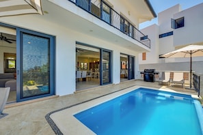 A modern house with a swimming pool, a balcony, and a dining area.