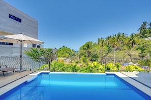 A swimming pool with a view of a modern building and tropical vegetation.