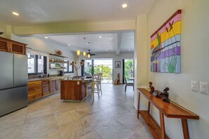 A spacious kitchen with a central island, wooden cabinets, and a dining area with chairs.