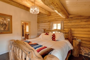 A log cabin bedroom with a wooden bed, a chandelier, and a painting on the wall. - Durango Mountain Escape w/ Stunning Views (Durango)