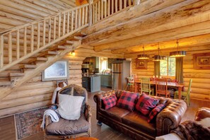 A log cabin interior with a staircase, a living room with a sofa and chairs, a dining area, and a kitchen. - Durango Mountain Escape w/ Stunning Views (Durango)