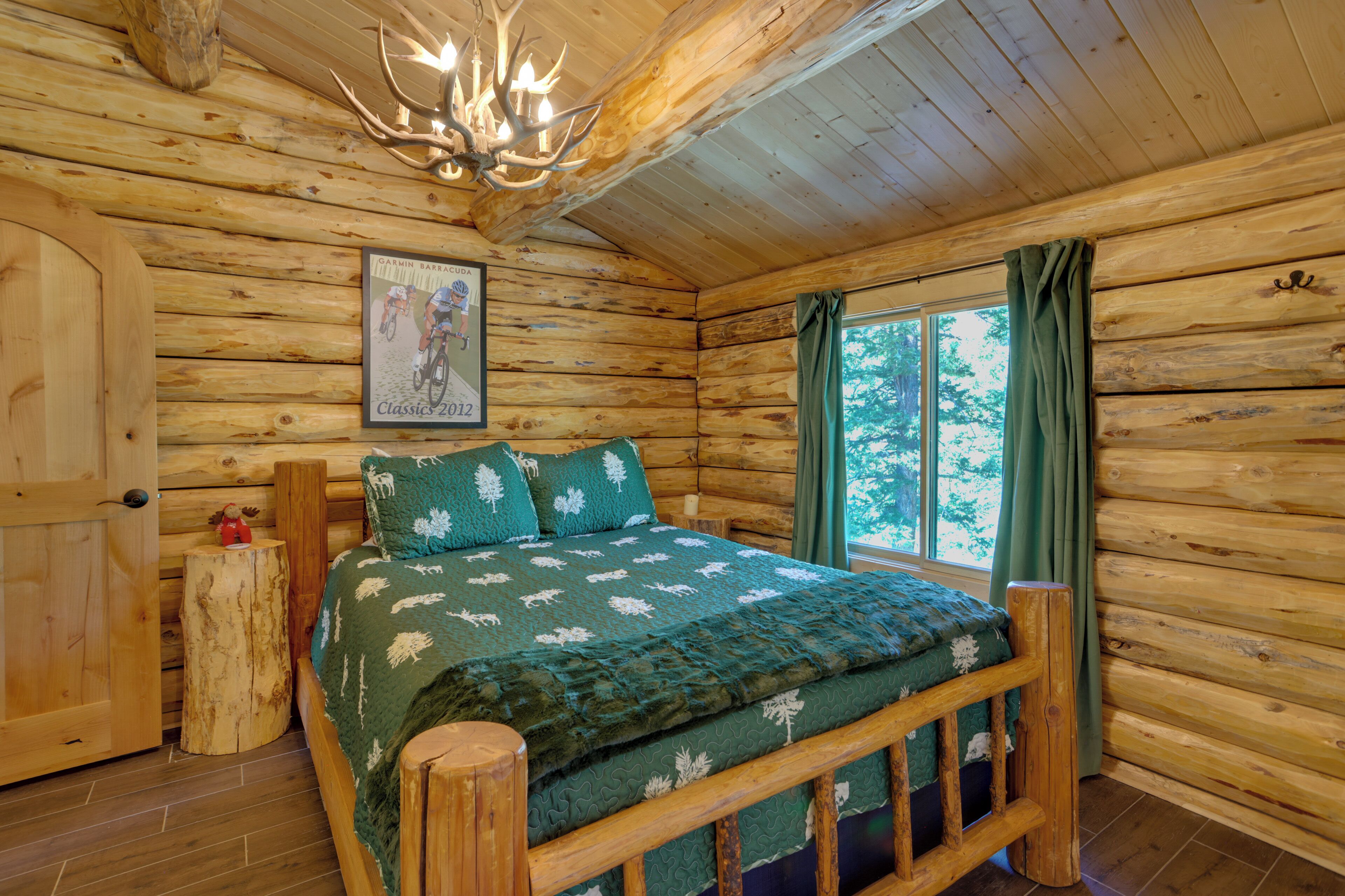 A log cabin bedroom with a bed, a mounted picture, and a window with curtains.