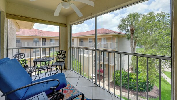 A balcony with a ceiling fan, a blue sofa, and a small table with chairs. - Golf On-site! Extended Stay 4 Mi to Dtwn Naples (Naples)