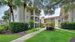 A multi-story hotel with balconies, a central courtyard, and well-maintained landscaping. - Golf On-site! Extended Stay 4 Mi to Dtwn Naples (Naples)