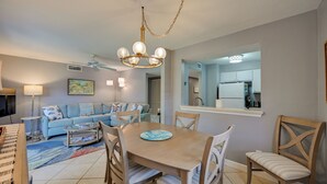 A dining area with a wooden table and chairs, a sofa, a coffee table, and a chandelier. - Golf On-site! Extended Stay 4 Mi to Dtwn Naples (Naples)