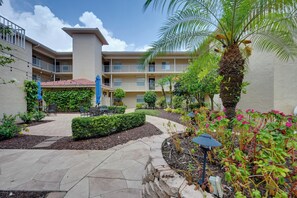 A courtyard with a palm tree, outdoor seating, and a building with balconies. - Golf On-site! Extended Stay 4 Mi to Dtwn Naples (Naples)