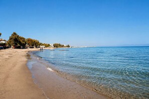 A beach with clear water, a sandy shore, and trees in the background. - Artemida Olive Gem - Sunny Balcony Views Parking (Spata-Artemida)