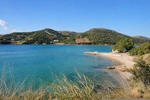 A coastal landscape with clear water, a sandy beach, and hills in the background. - Artemida Olive Gem - Sunny Balcony Views Parking (Spata-Artemida)