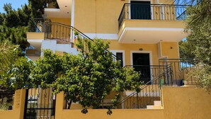 A multi-story building with balconies, a staircase, and a tree in the foreground.